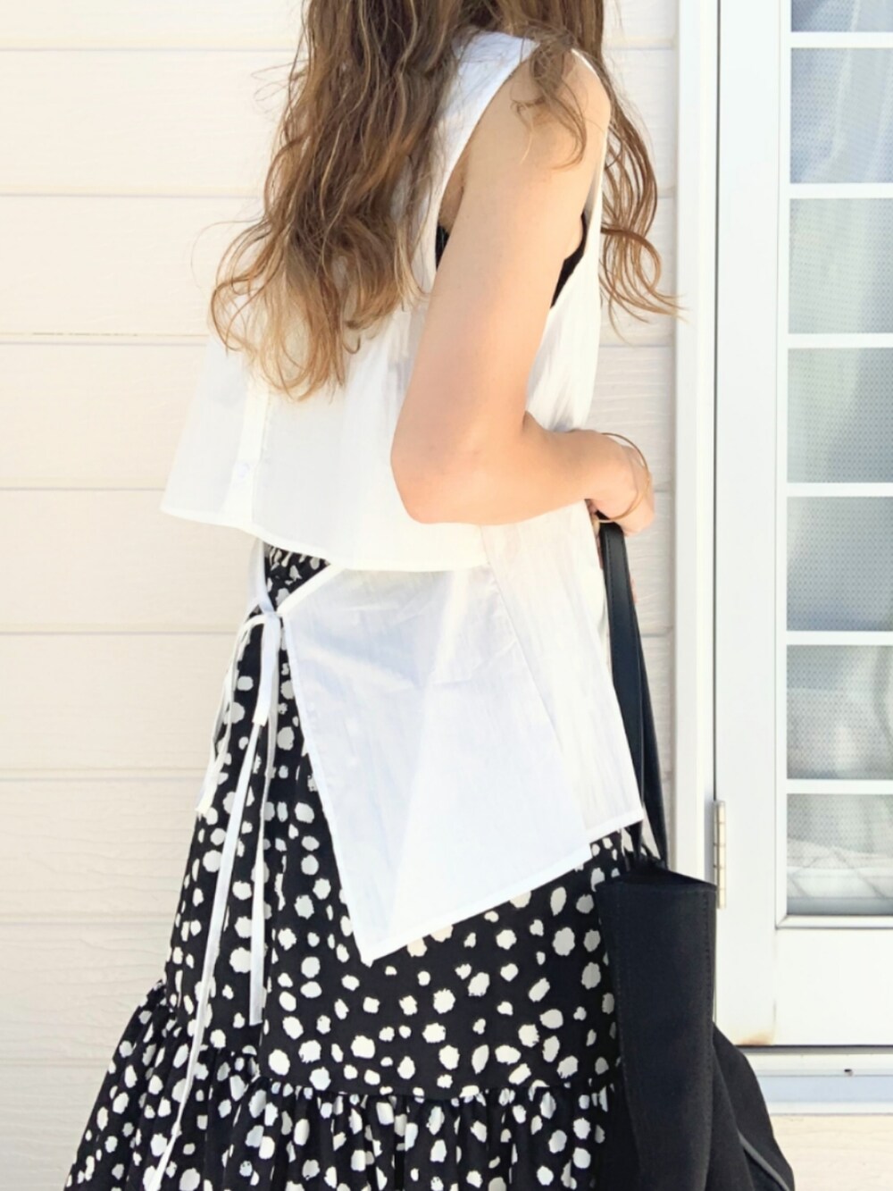 ブラック系のスカート、ホワイト系のトートバッグ、ホワイト系のシャツ/ブラウスを着用したレディースの夏コーディネートの5枚目の写真