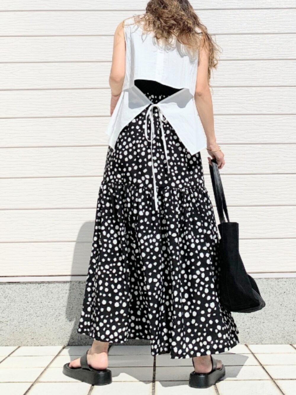 ブラック系のスカート、ホワイト系のトートバッグ、ホワイト系のシャツ/ブラウスを着用したレディースの夏コーディネートの3枚目の写真