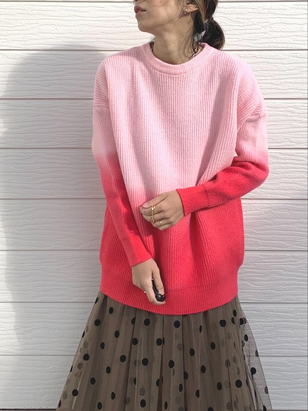 ピンク系のニット/セーター、ブラウン系のスカート、ブラック系のスニーカーを着用したレディースの冬コーディネートの4枚目の写真