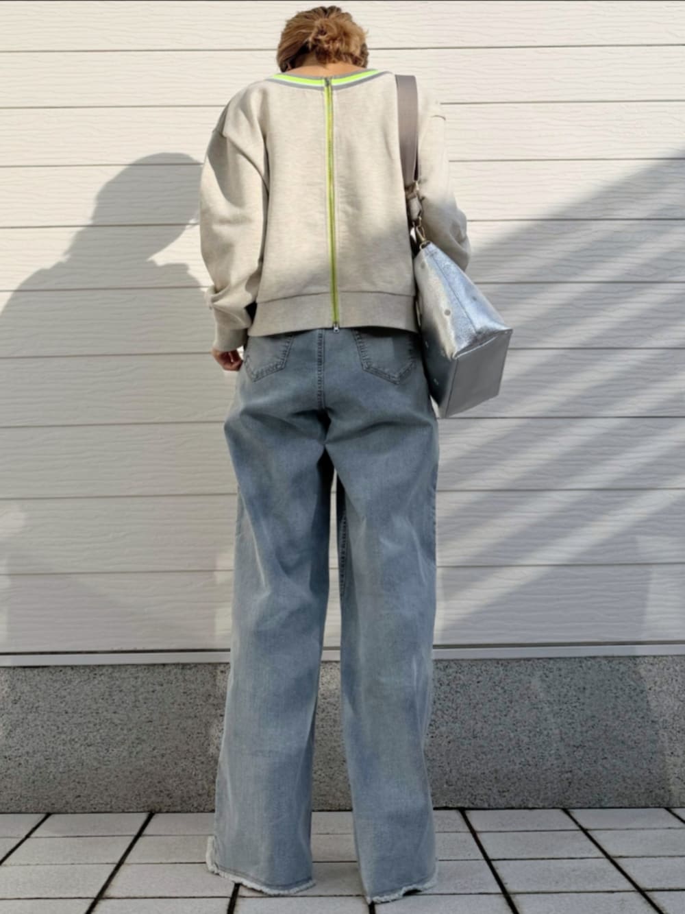 ブルー系のデニムパンツ、シルバー系のトートバッグ、グレー系のカーディガン/ボレロを着用したレディースの冬コーディネートの3枚目の写真