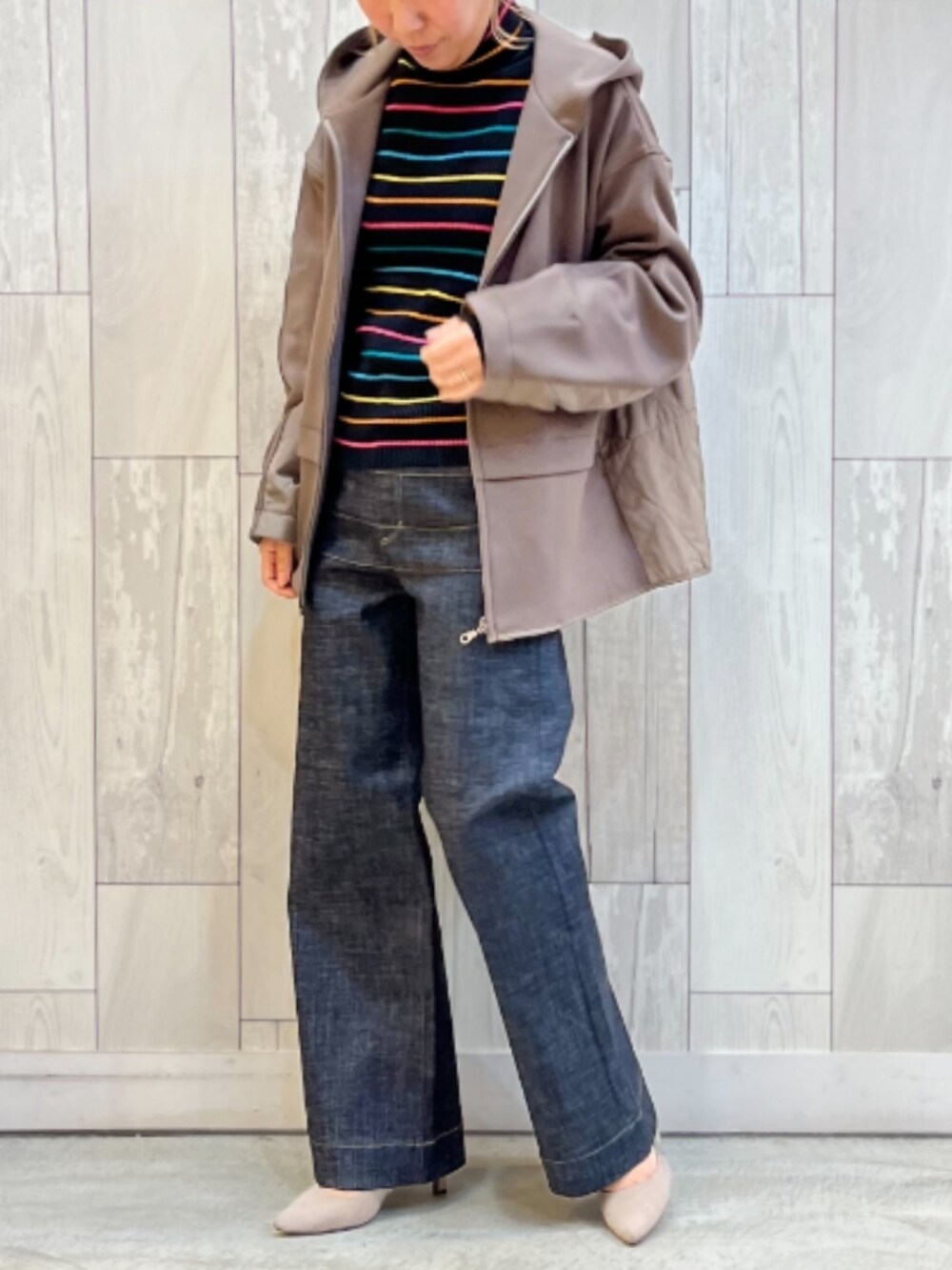 ブルー系のデニムパンツ、ベージュ系のパーカー、ブラック系のニット/セーターを着用したレディースの秋コーディネートの2枚目の写真