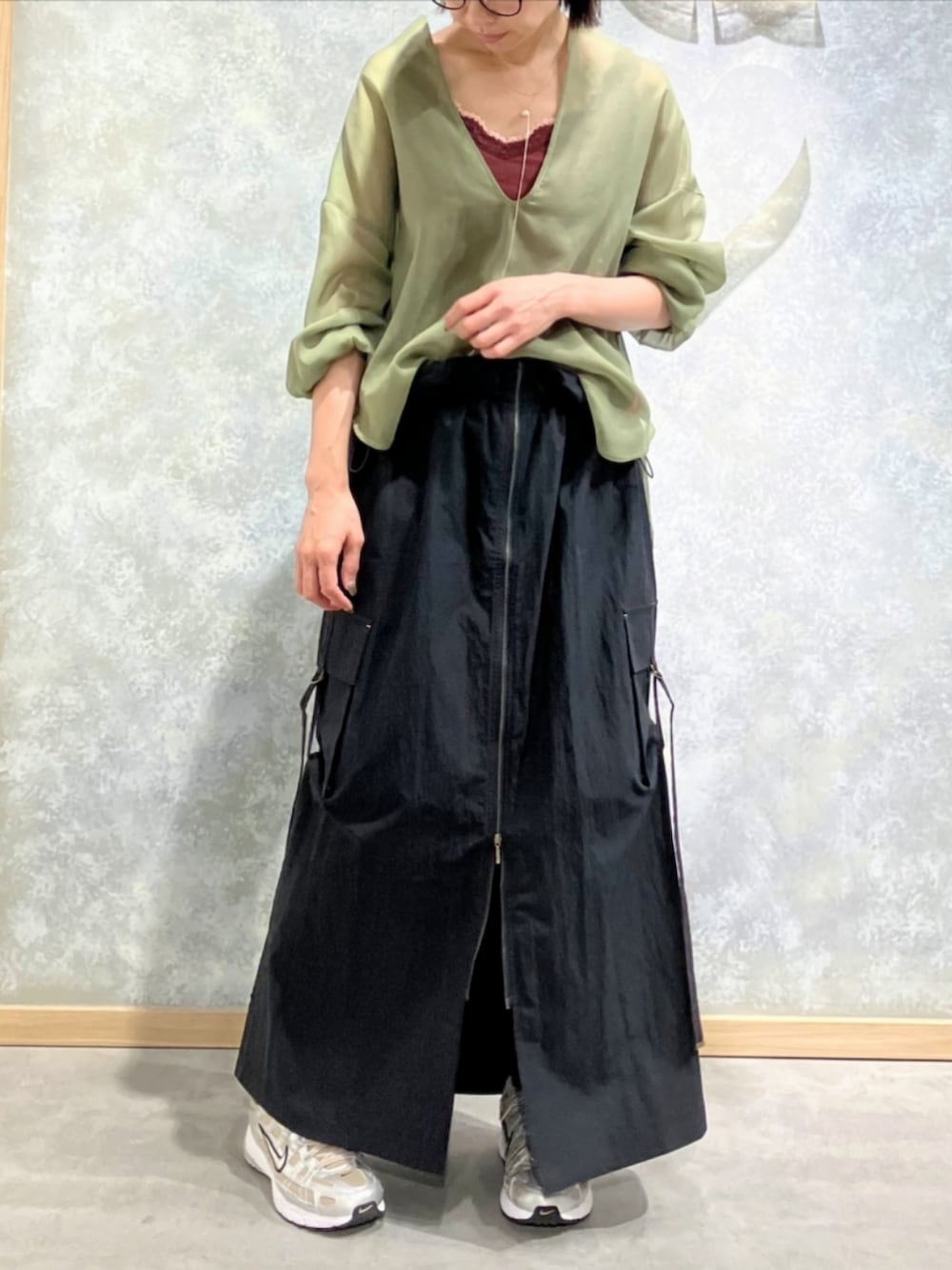 ブラック系のジャンパースカート、グリーン系のシャツ/ブラウス、レッド系のタンクトップを着用したレディースの秋コーディネートの2枚目の写真