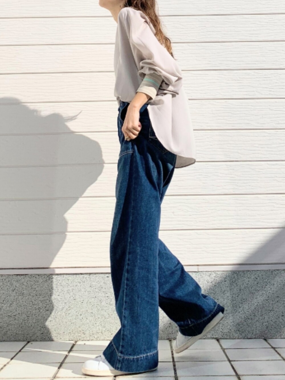 ブルー系のデニムパンツ、ホワイト系のスニーカー、ベージュ系のシャツ/ブラウスを着用したレディースの冬コーディネートの3枚目の写真