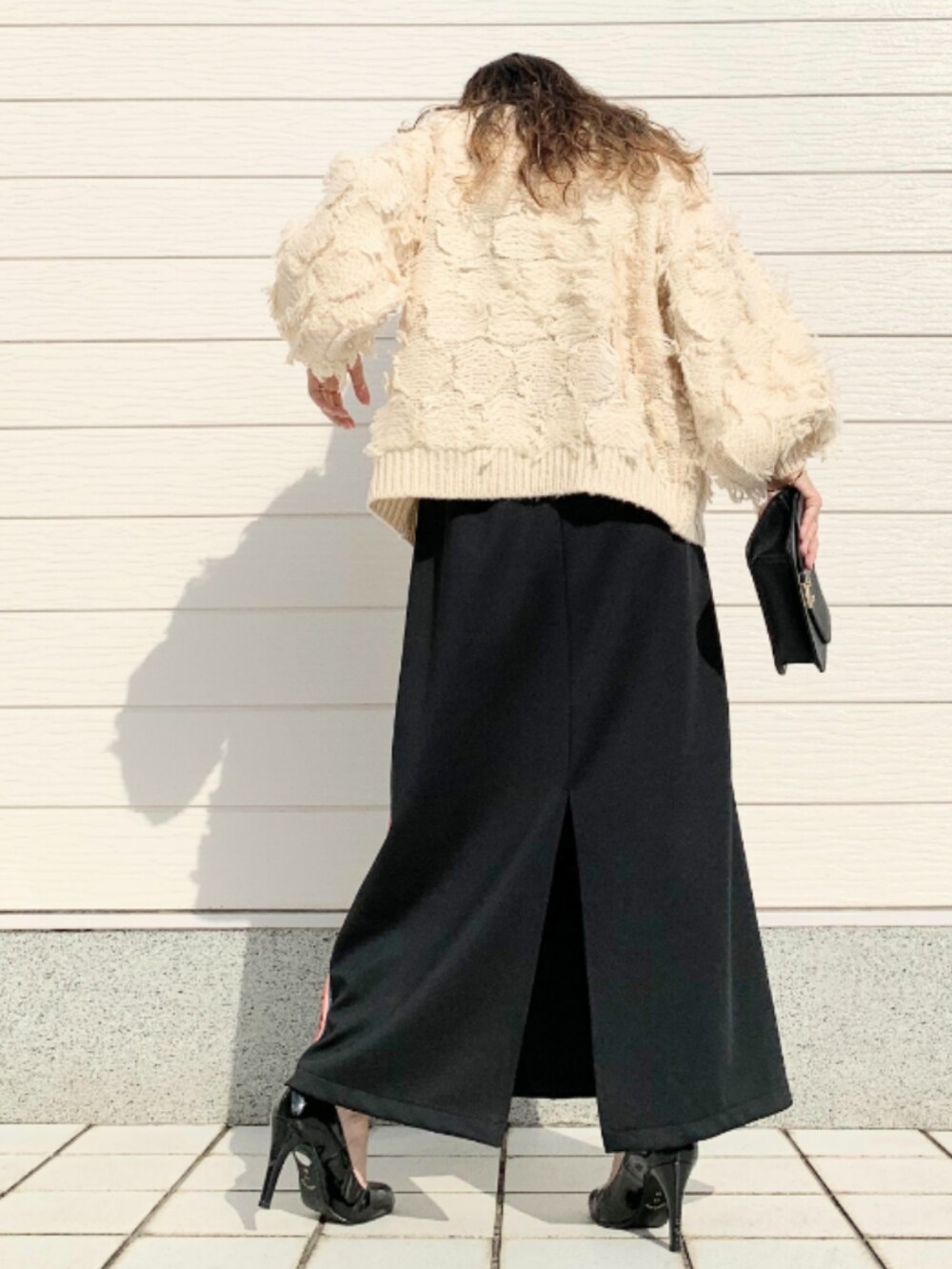 ブラック系のスカート、ホワイト系のニット/セーターを着用したレディースの秋コーディネートの3枚目の写真