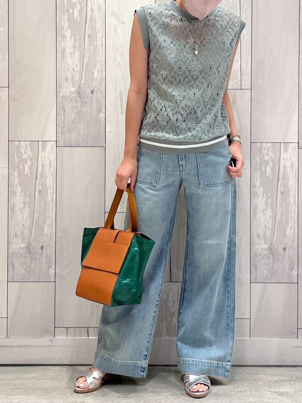 グリーン系のトートバッグ、ブルー系のデニムパンツ、グリーン系のTシャツ/カットソーを着用したレディースの夏コーディネートの2枚目の写真