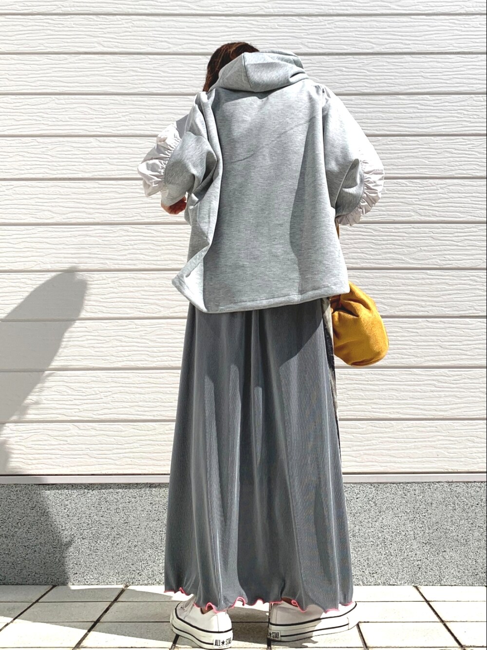 ホワイト系のスニーカー、ベージュ系のスカート、イエロー系のショルダーバッグを着用したレディースの春コーディネートの2枚目の写真