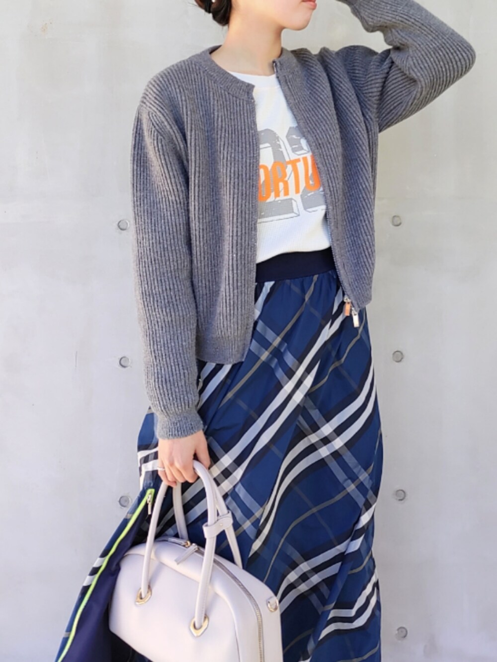 ホワイト系のボストンバッグ、ブルー系のスカート、ホワイト系のスニーカーを着用したレディースの冬コーディネートの2枚目の写真