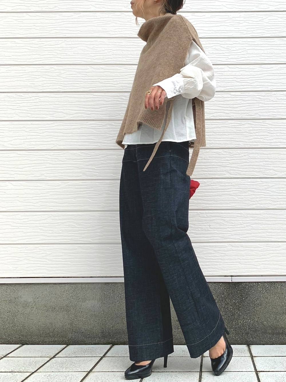 イエロー系のベスト、レッド系のショルダーバッグ、ブルー系のデニムパンツを着用したレディースの秋コーディネートの2枚目の写真