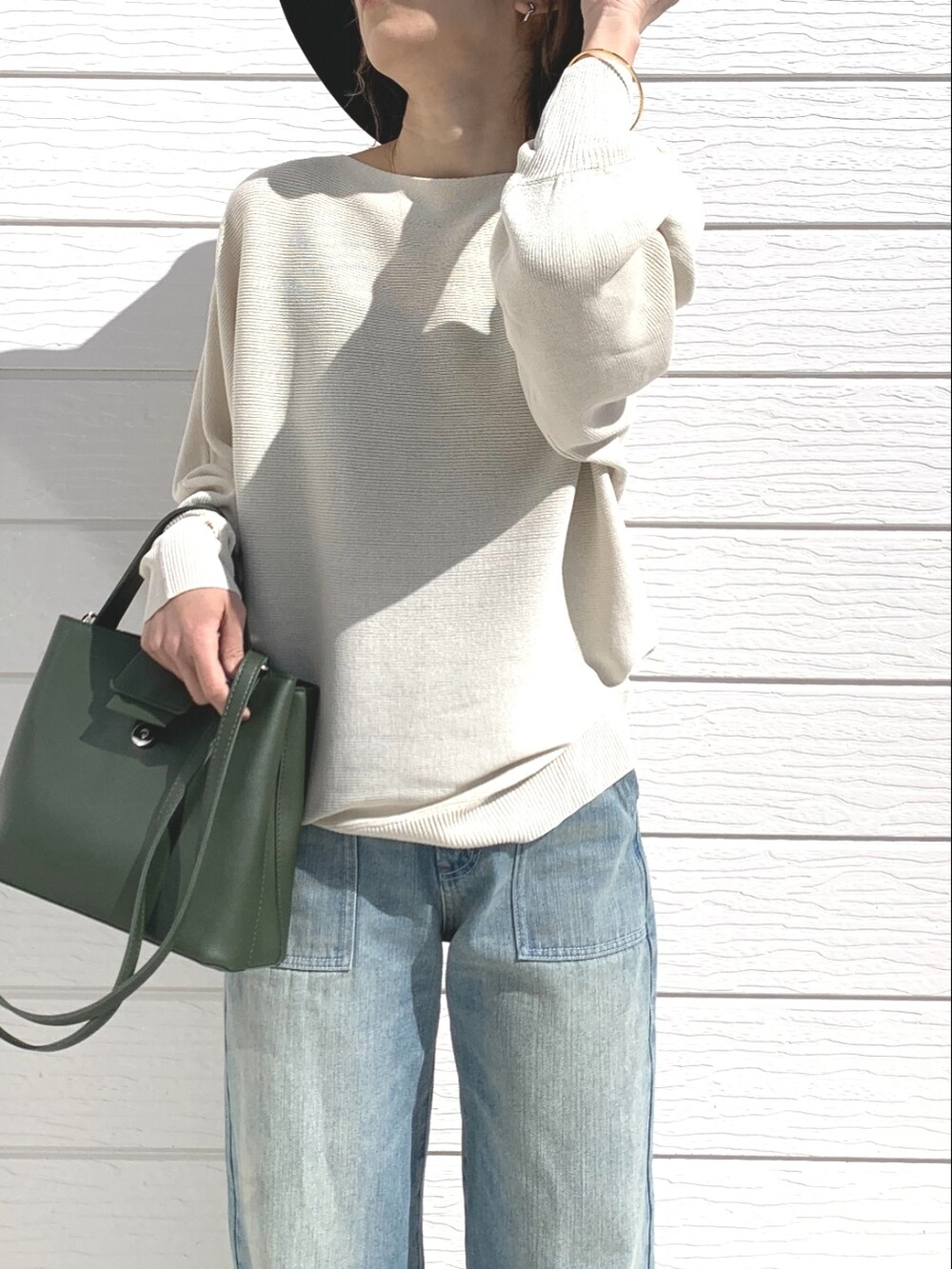 ブルー系のデニムパンツ、グリーン系のハンドバッグ、ブラック系のサンダルを着用したレディースの春コーディネートの3枚目の写真