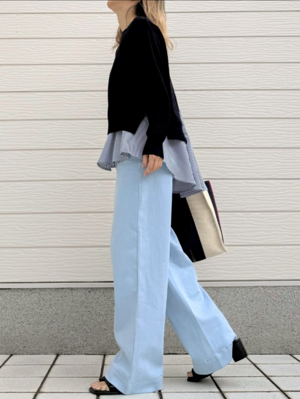 ブルー系のデニムパンツ、ブルー系のニット/セーター、ブラック系のサンダルを着用したレディースの春コーディネートの2枚目の写真