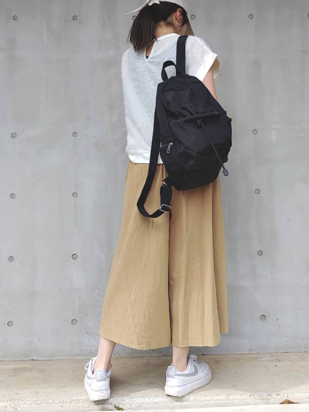 イエロー系のその他パンツ、ホワイト系のスニーカー、ブラック系のバックパック/リュックを着用したレディースの春コーディネートの3枚目の写真