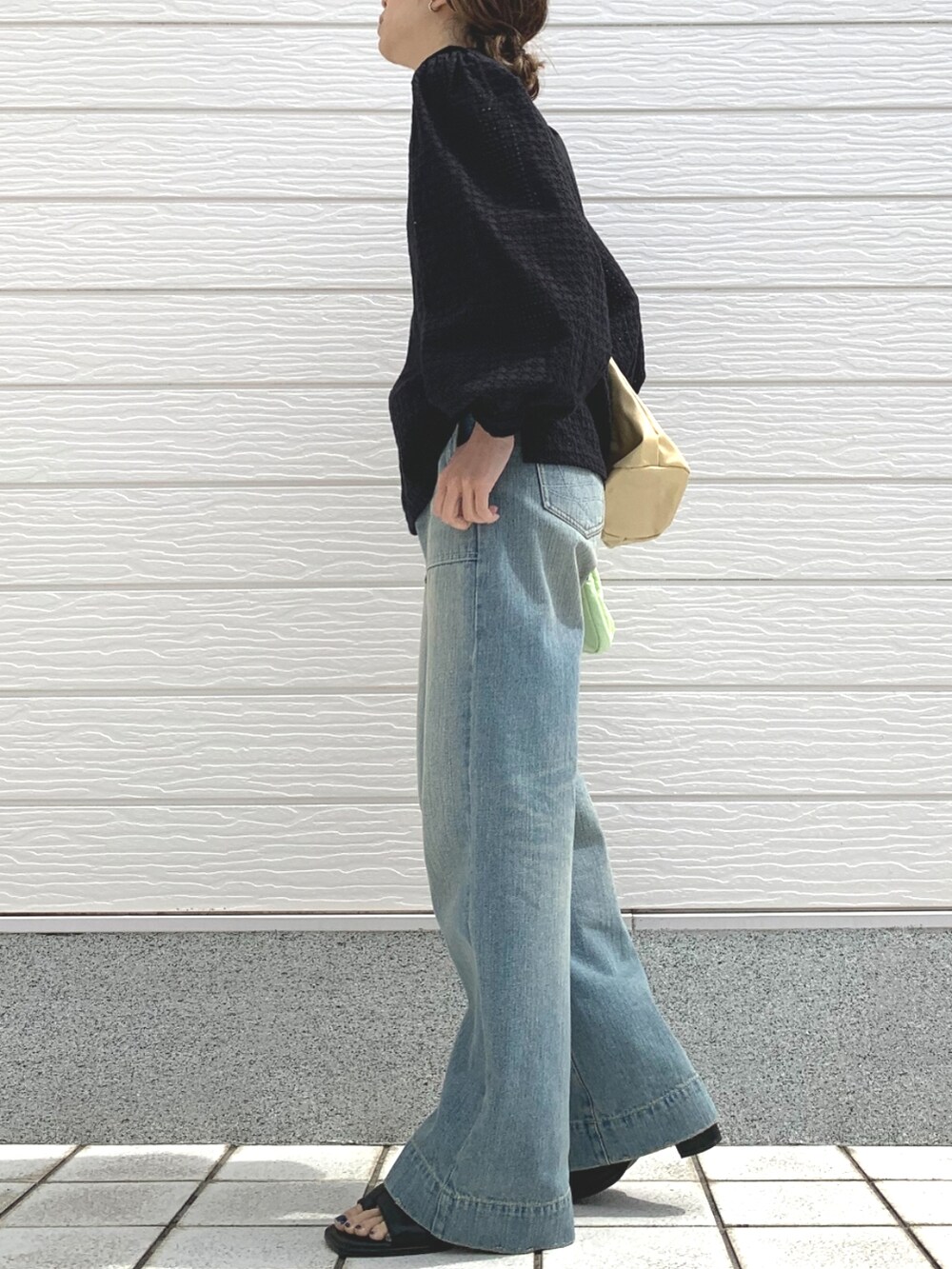 ブルー系のデニムパンツ、ベージュ系のショルダーバッグ、ブラック系のシャツ/ブラウスを着用したレディースの春コーディネートの2枚目の写真