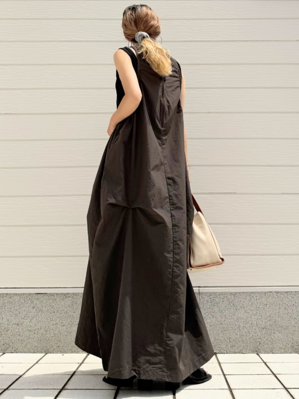 ブラック系のサンダル、ホワイト系のハンドバッグ、グレー系のワンピースを着用したレディースの夏コーディネートの3枚目の写真