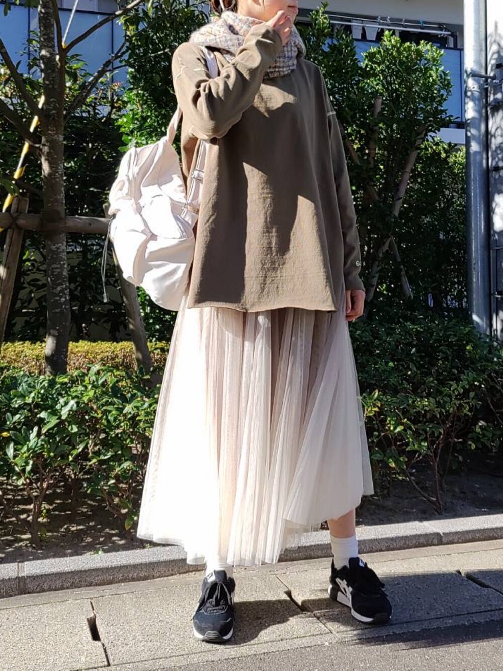 グリーン系のTシャツ/カットソー、ホワイト系のバックパック/リュック、ゴールド系のスカートを着用したレディースの秋コーディネートの2枚目の写真