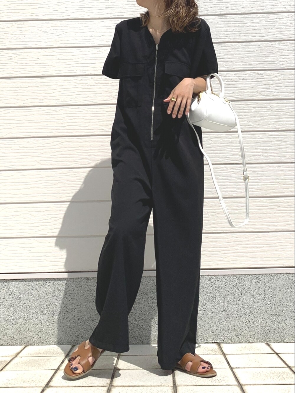 イエロー系のサンダル、ブラック系のつなぎ/オールインワン、ホワイト系のショルダーバッグを着用したレディースの春コーディネートの2枚目の写真
