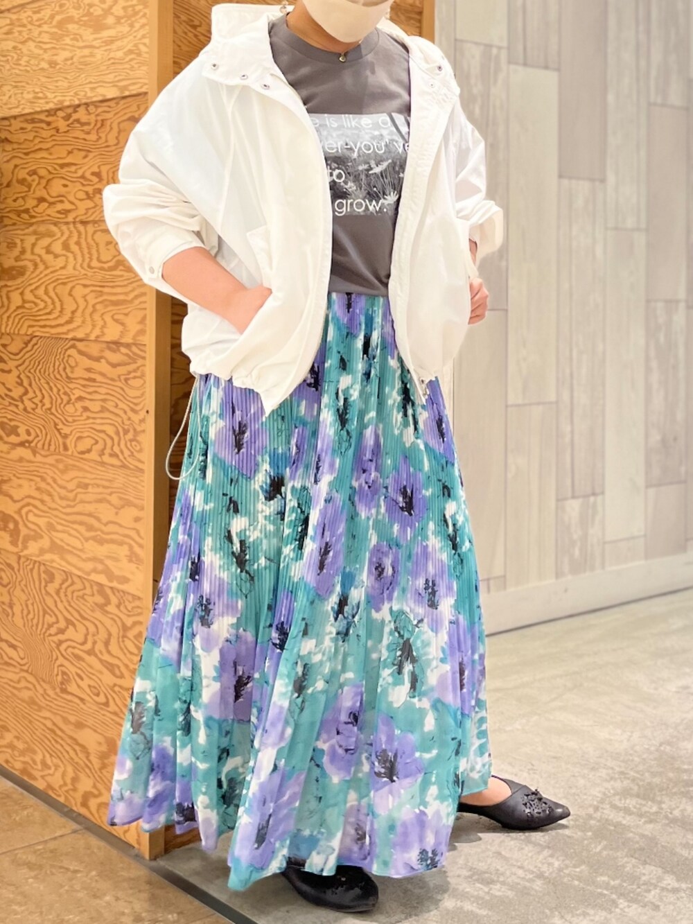 グリーン系のスカート、グレー系のTシャツ/カットソー、ホワイト系のマウンテンパーカーを着用したレディースの春コーディネートの2枚目の写真