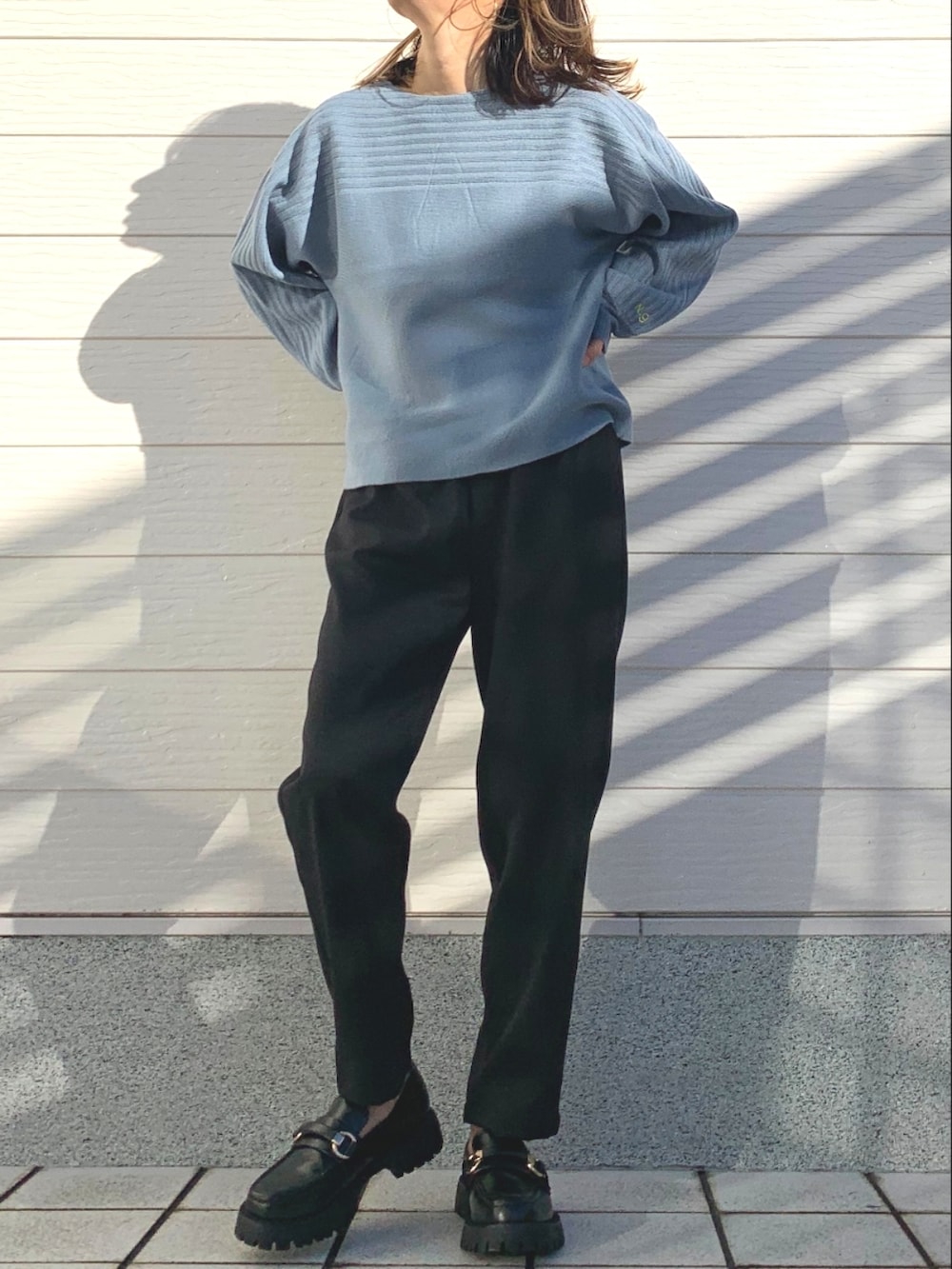 ブラック系のその他パンツ、ブラック系のローファー、ブルー系のニット/セーターを着用したレディースの冬コーディネートの2枚目の写真