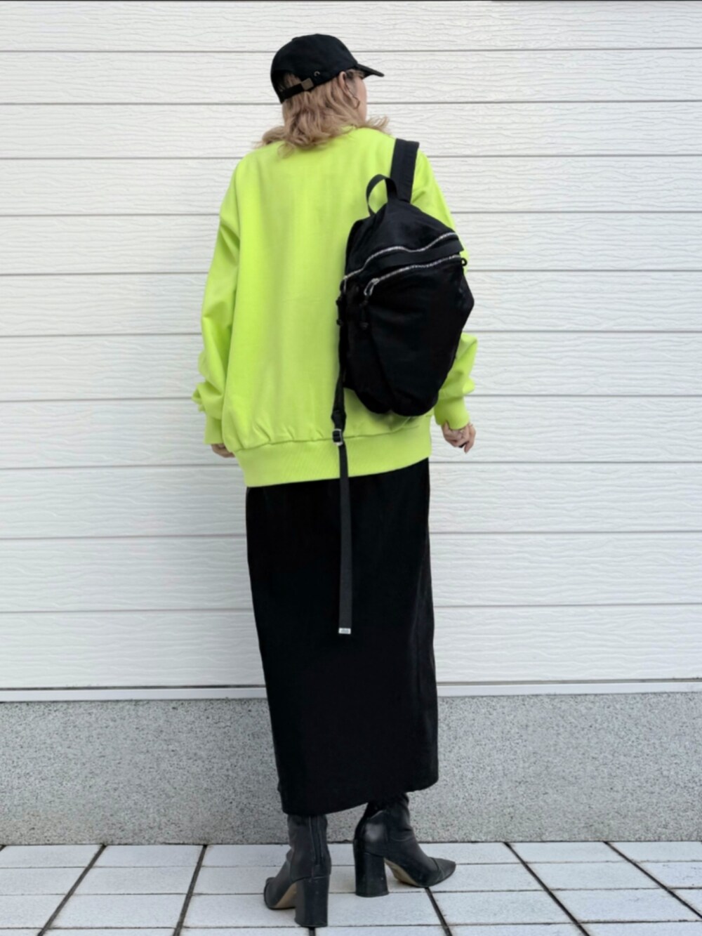 ブラック系のスカート、ホワイト系のTシャツ/カットソー、ブラック系のバックパック/リュックを着用したレディースの秋コーディネートの2枚目の写真