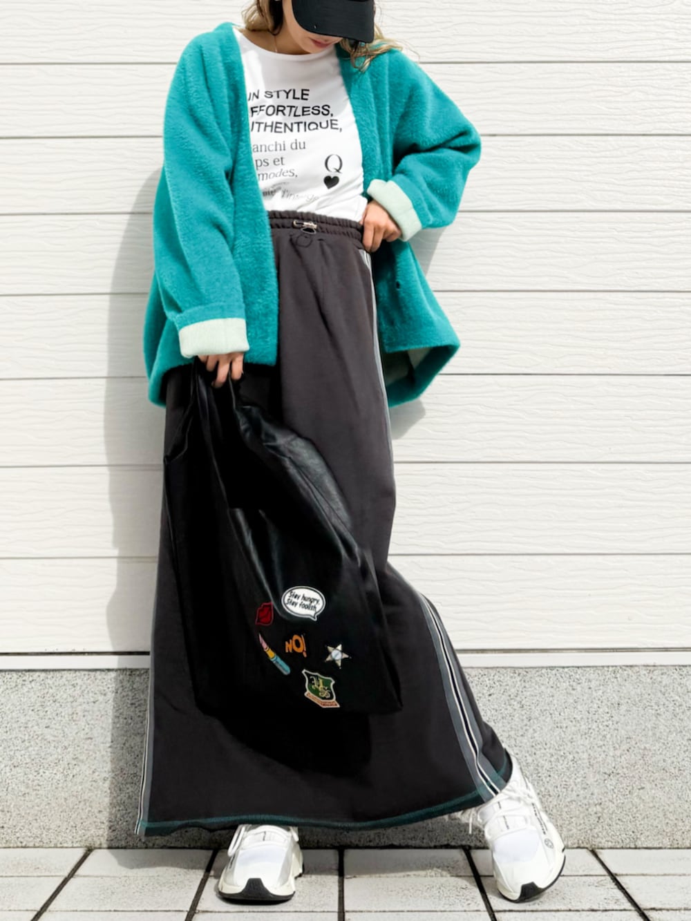 グレー系のスカート、ホワイト系のTシャツ/カットソー、グリーン系のカーディガン/ボレロを着用したレディースの秋コーディネートの3枚目の写真