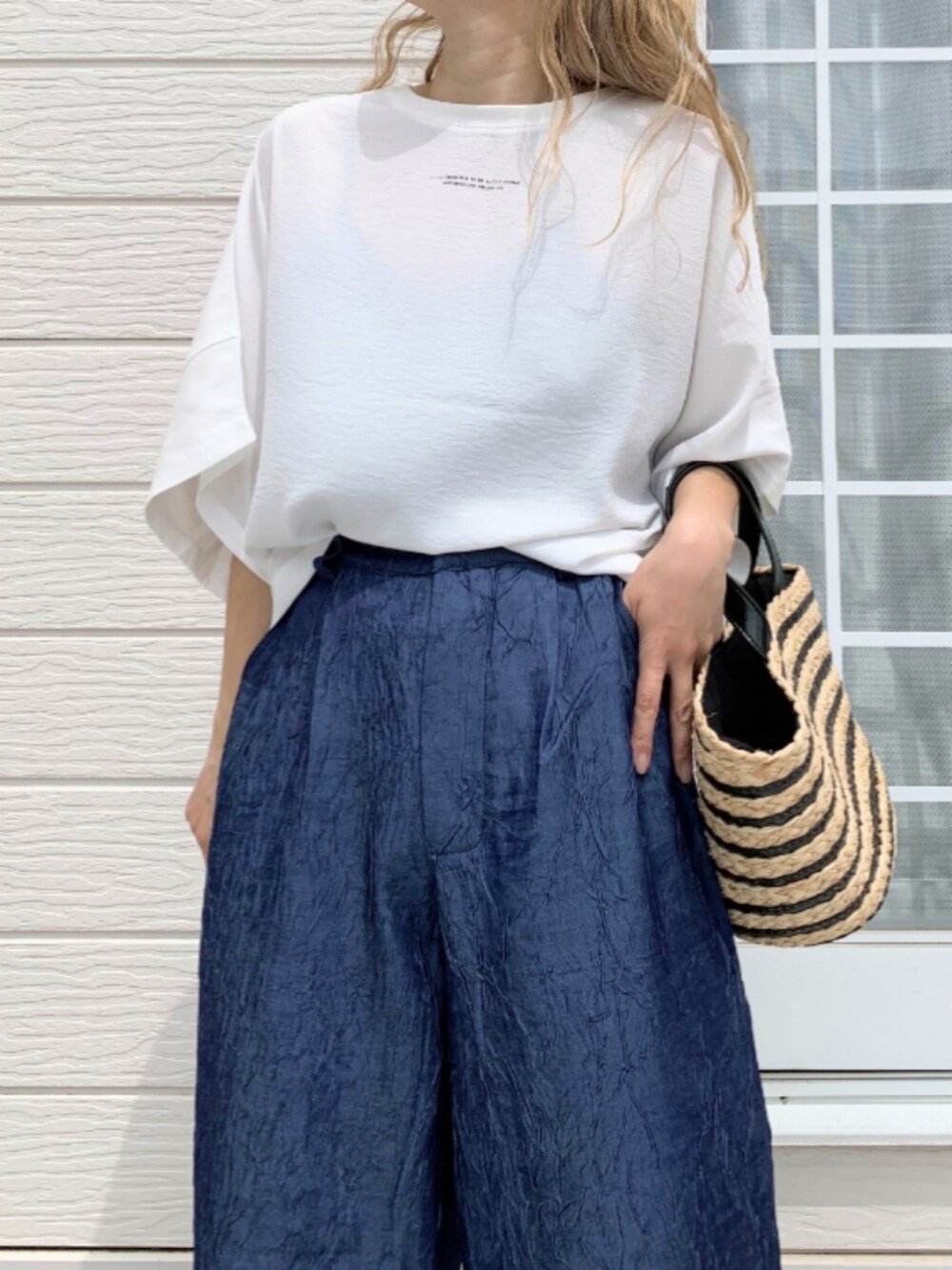 ホワイト系のTシャツ/カットソー、ブラック系のかごバッグ、ブルー系のデニムパンツを着用したレディースの春コーディネートの5枚目の写真