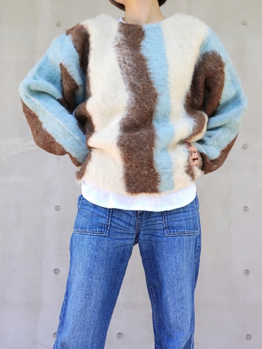 ブルー系のデニムパンツ、ブルー系のニット/セーター、ブラック系のスニーカーを着用したレディースの秋コーディネートの4枚目の写真