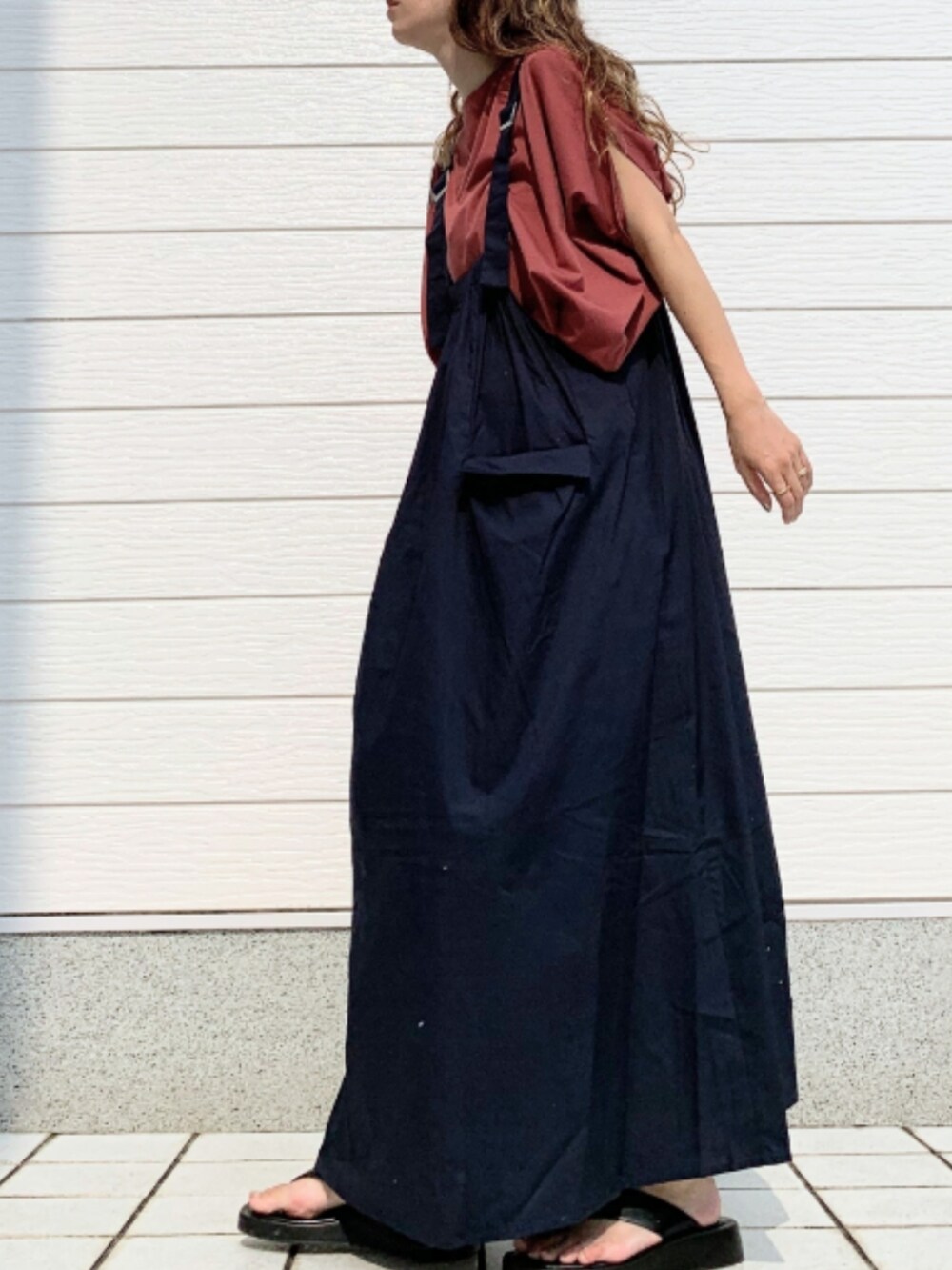 レッド系のTシャツ/カットソー、ブルー系のジャンパースカート、ホワイト系のボストンバッグを着用したレディースの夏コーディネートの2枚目の写真