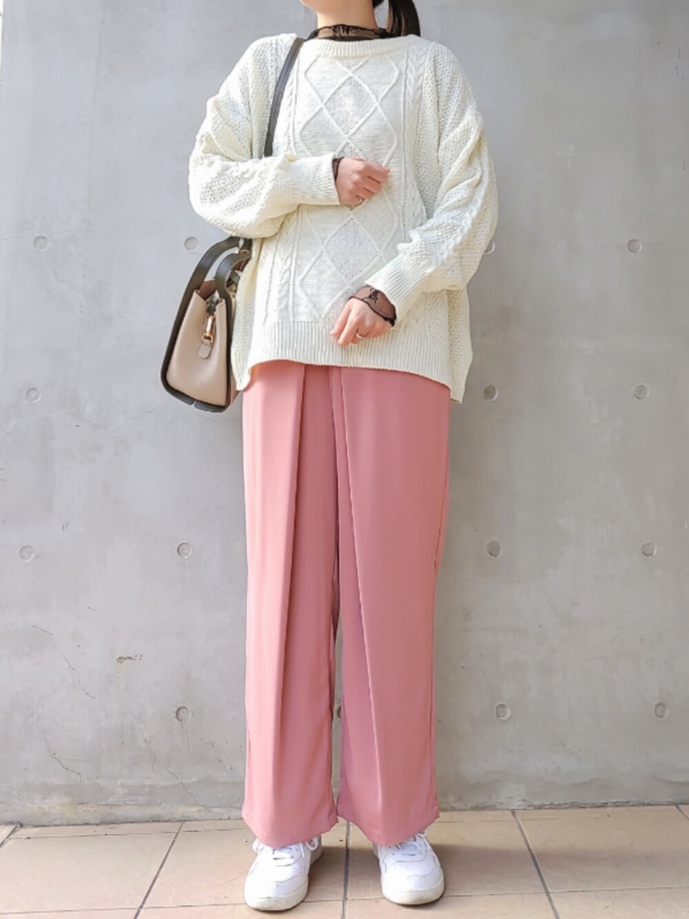 ピンク系のスラックス、ホワイト系のスニーカー、ホワイト系のニット/セーターを着用したレディースの冬コーディネートの2枚目の写真