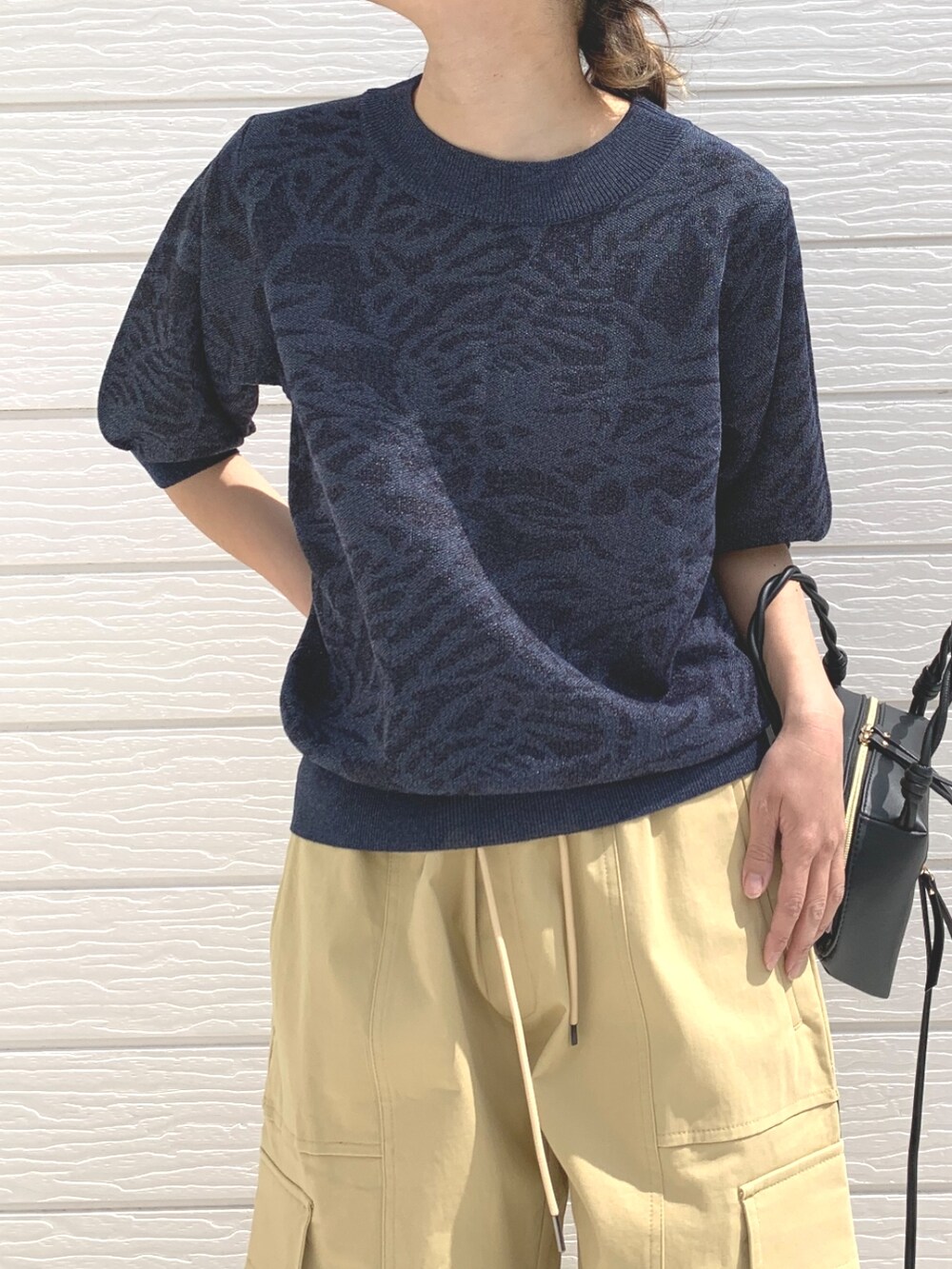 ブラック系のハンドバッグ、ブルー系のニット/セーター、ベージュ系のその他パンツを着用したレディースの春コーディネートの4枚目の写真