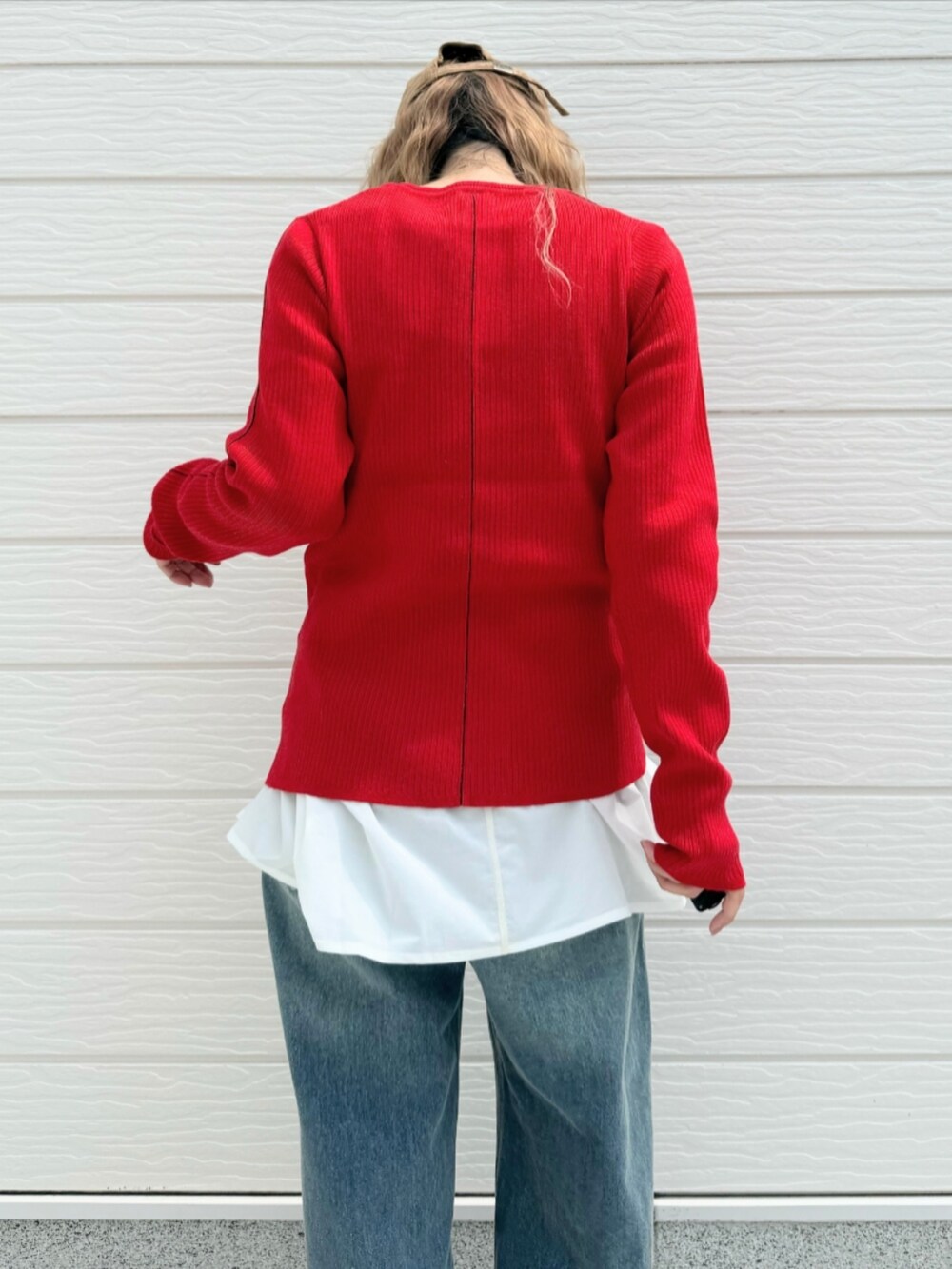 レッド系のニット/セーター、ブルー系のデニムパンツ、ホワイト系のTシャツ/カットソーを着用したレディースの秋コーディネートの5枚目の写真