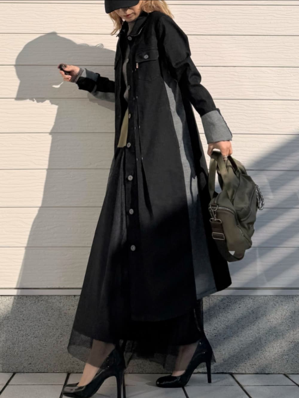 グリーン系のスカート、グリーン系のボストンバッグ、ブラック系のデニムジャケットを着用したレディースの冬コーディネートの2枚目の写真