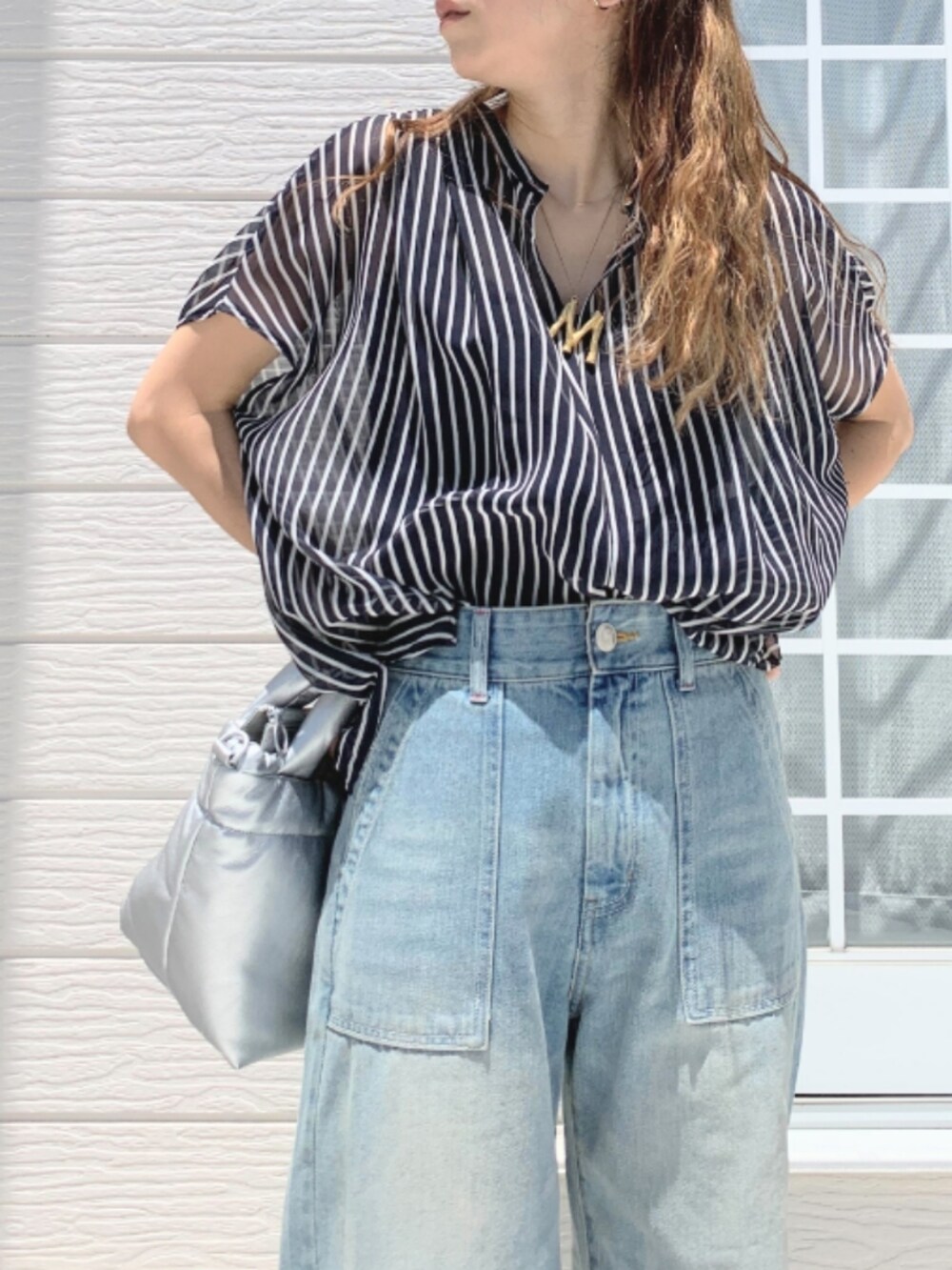 シルバー系のショルダーバッグ、ブルー系のデニムパンツ、ブルー系のシャツ/ブラウスを着用したレディースの夏コーディネートの3枚目の写真