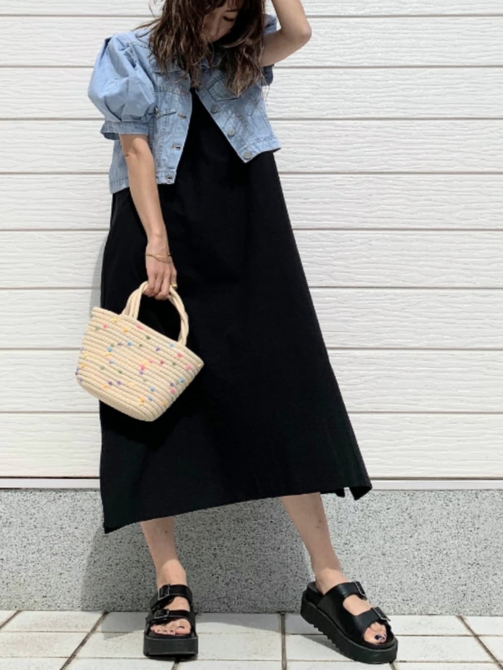 ブラック系のサンダル、ホワイト系のかごバッグ、ブルー系のデニムジャケットを着用したレディースの夏コーディネートの2枚目の写真