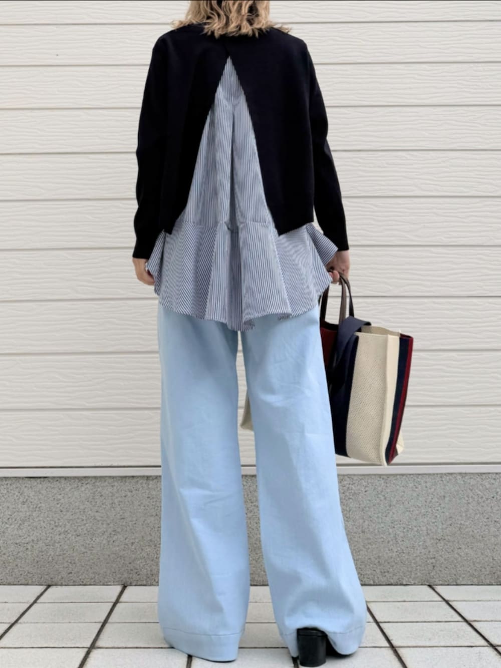 ブルー系のデニムパンツ、ブルー系のニット/セーター、ブラック系のサンダルを着用したレディースの春コーディネートの3枚目の写真