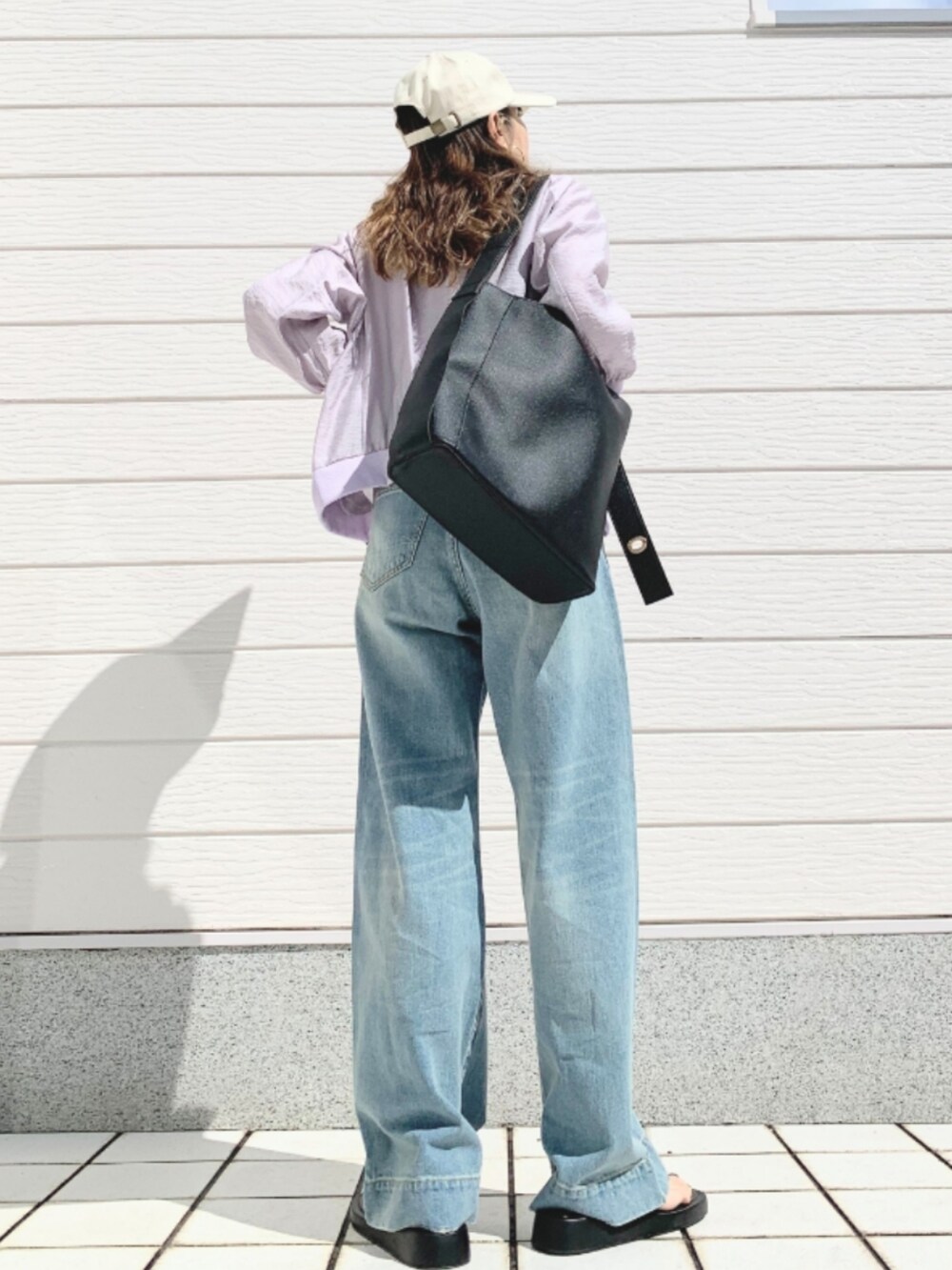 グレー系のキャミソール、グレー系のブルゾン、ブルー系のデニムパンツを着用したレディースの春コーディネートの3枚目の写真