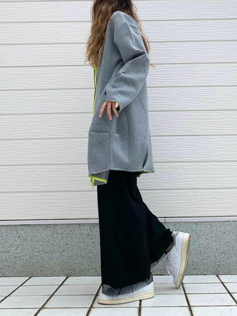 グレー系のクラッチバッグ、ホワイト系のスニーカー、ブラック系のTシャツ/カットソーを着用したレディースの秋コーディネートの4枚目の写真