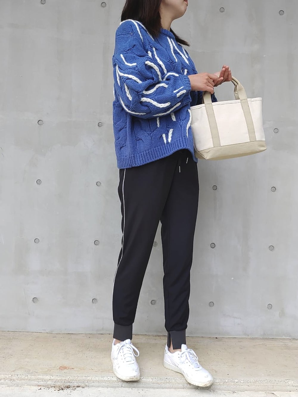 ブラック系のその他パンツ、ブルー系のニット/セーター、ベージュ系のトートバッグを着用したレディースの秋コーディネートの2枚目の写真