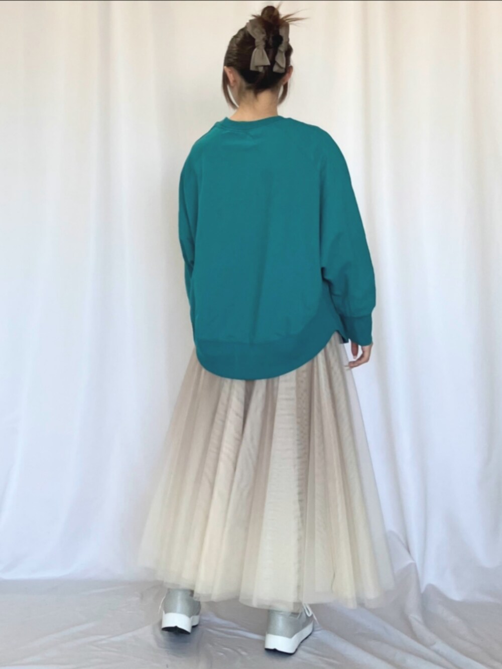 ゴールド系のスカート、グリーン系のスウェット、シルバー系のスニーカーを着用したレディースの冬コーディネートの2枚目の写真