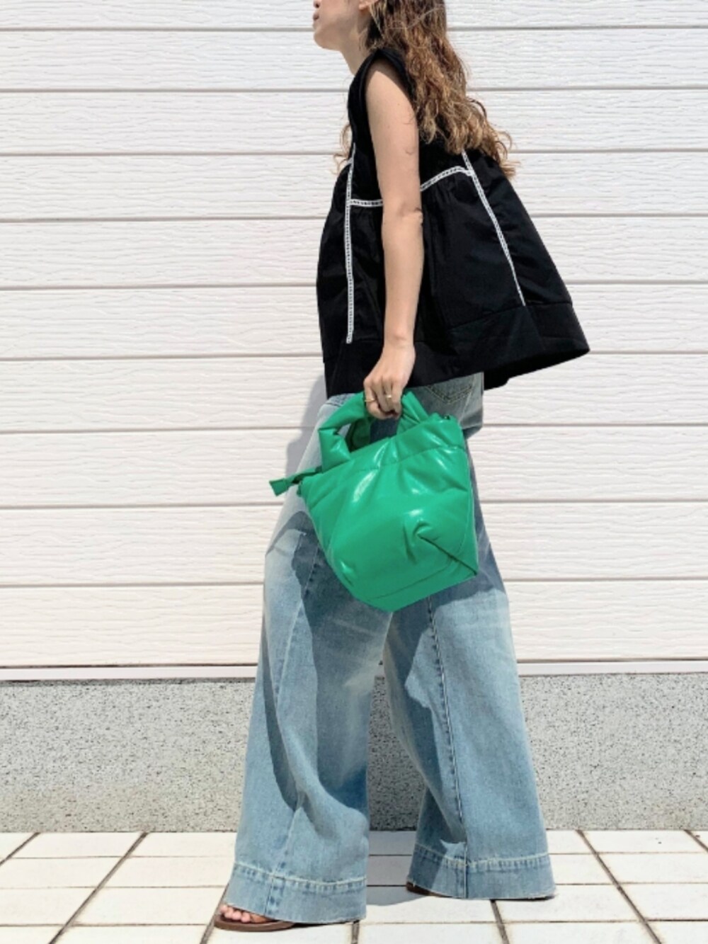 ブルー系のデニムパンツ、グリーン系のショルダーバッグ、ブラック系のシャツ/ブラウスを着用したレディースの夏コーディネートの2枚目の写真