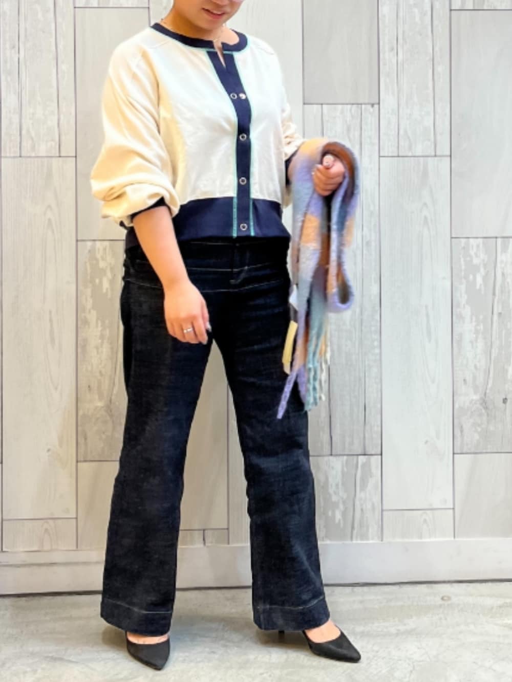 ブルー系のデニムパンツ、ホワイト系のカーディガン/ボレロ、オレンジ系のマフラーを着用したレディースの冬コーディネートの2枚目の写真