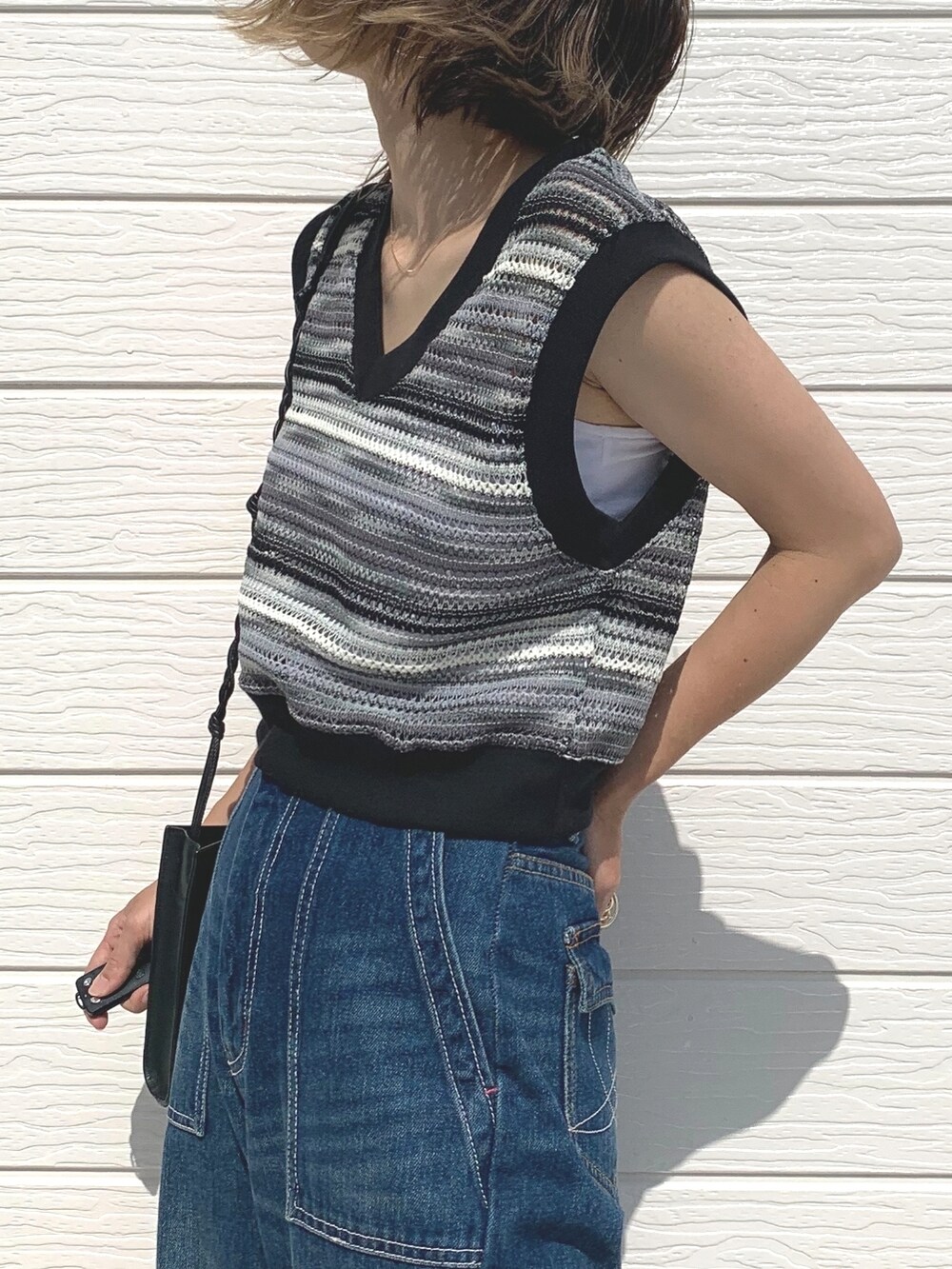 ブルー系のデニムパンツ、ホワイト系のキャミソール、ブラック系のベストを着用したレディースの夏コーディネートの3枚目の写真