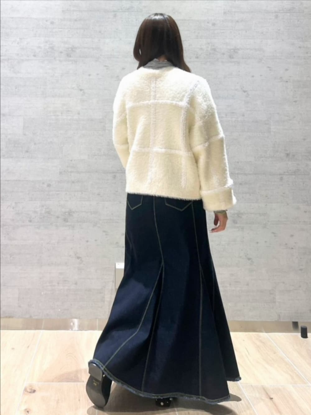 ブルー系のデニムスカート、ホワイト系のカーディガン/ボレロ、グレー系のTシャツ/カットソーを着用したレディースの冬コーディネートの2枚目の写真