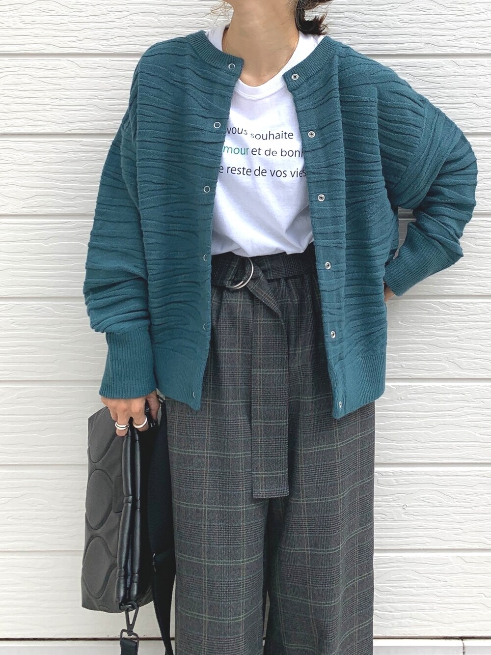 グリーン系のカーディガン/ボレロ、ホワイト系のTシャツ/カットソー、ブラック系のクラッチバッグを着用したレディースの秋コーディネートの3枚目の写真