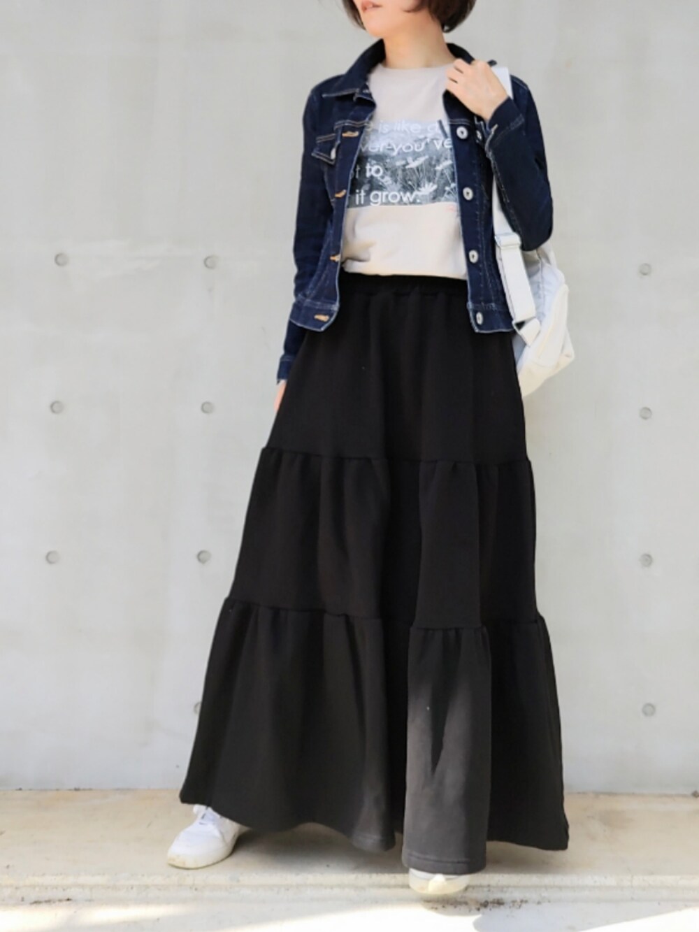 ブラック系のスカート、ホワイト系のバックパック/リュック、ベージュ系のTシャツ/カットソーを着用したレディースの秋コーディネートの2枚目の写真