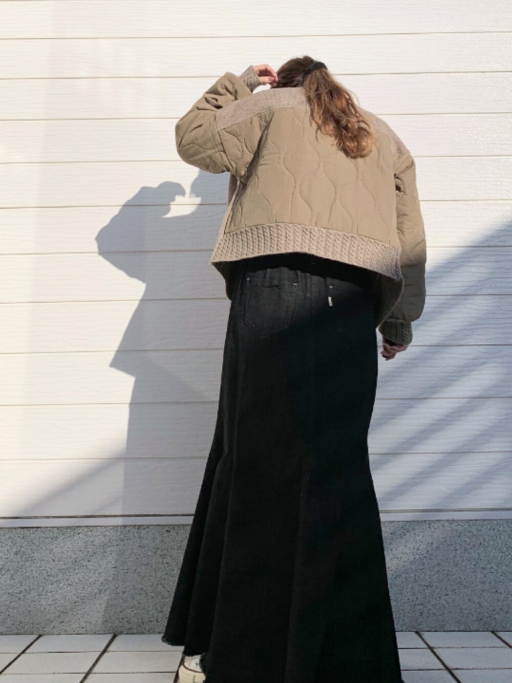 イエロー系のブルゾン、ホワイト系のTシャツ/カットソー、ブラック系のデニムスカートを着用したレディースの秋コーディネートの3枚目の写真