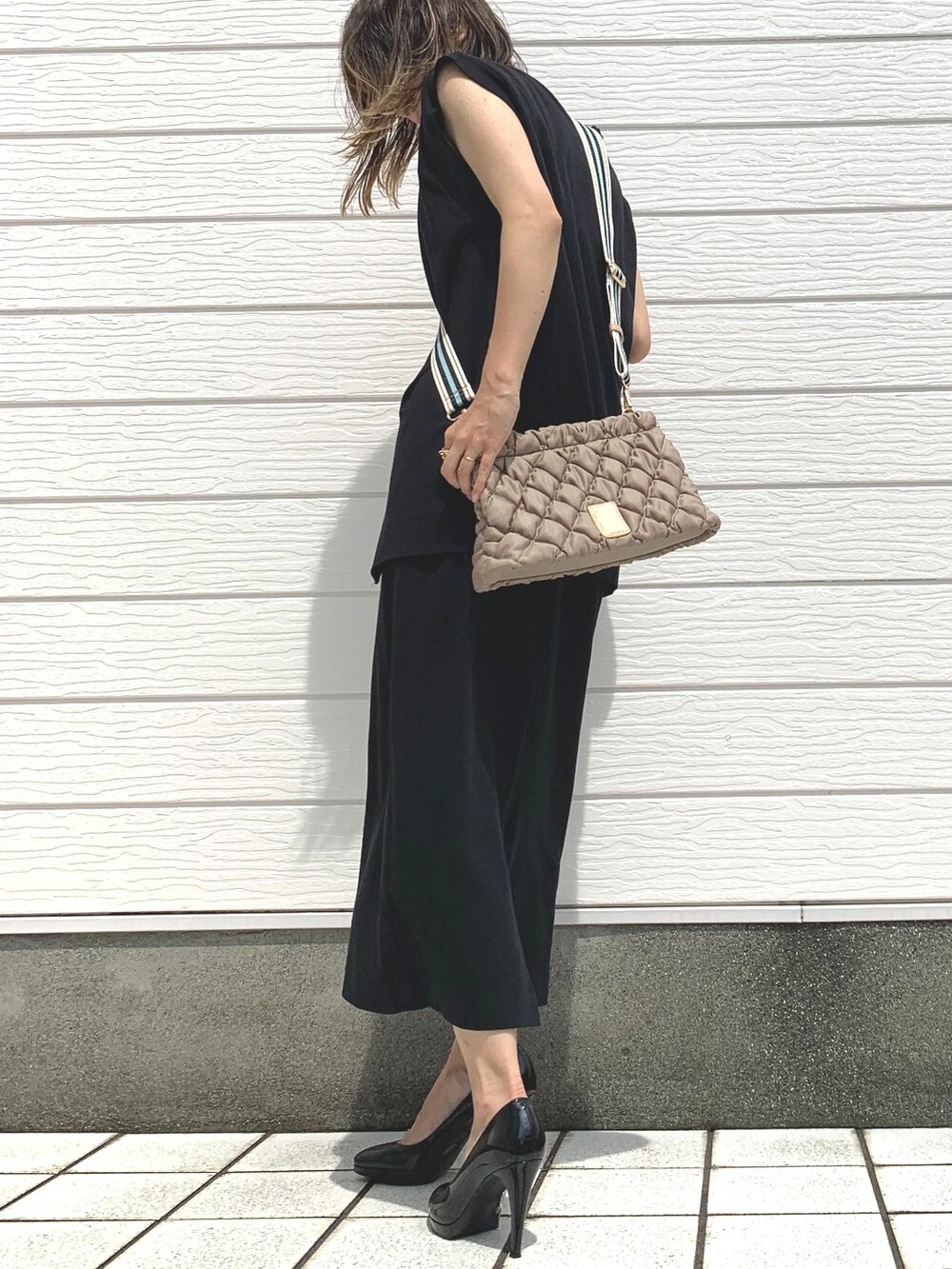 ブラック系のワンピース、ベージュ系のショルダーバッグを着用したレディースの夏コーディネートの2枚目の写真