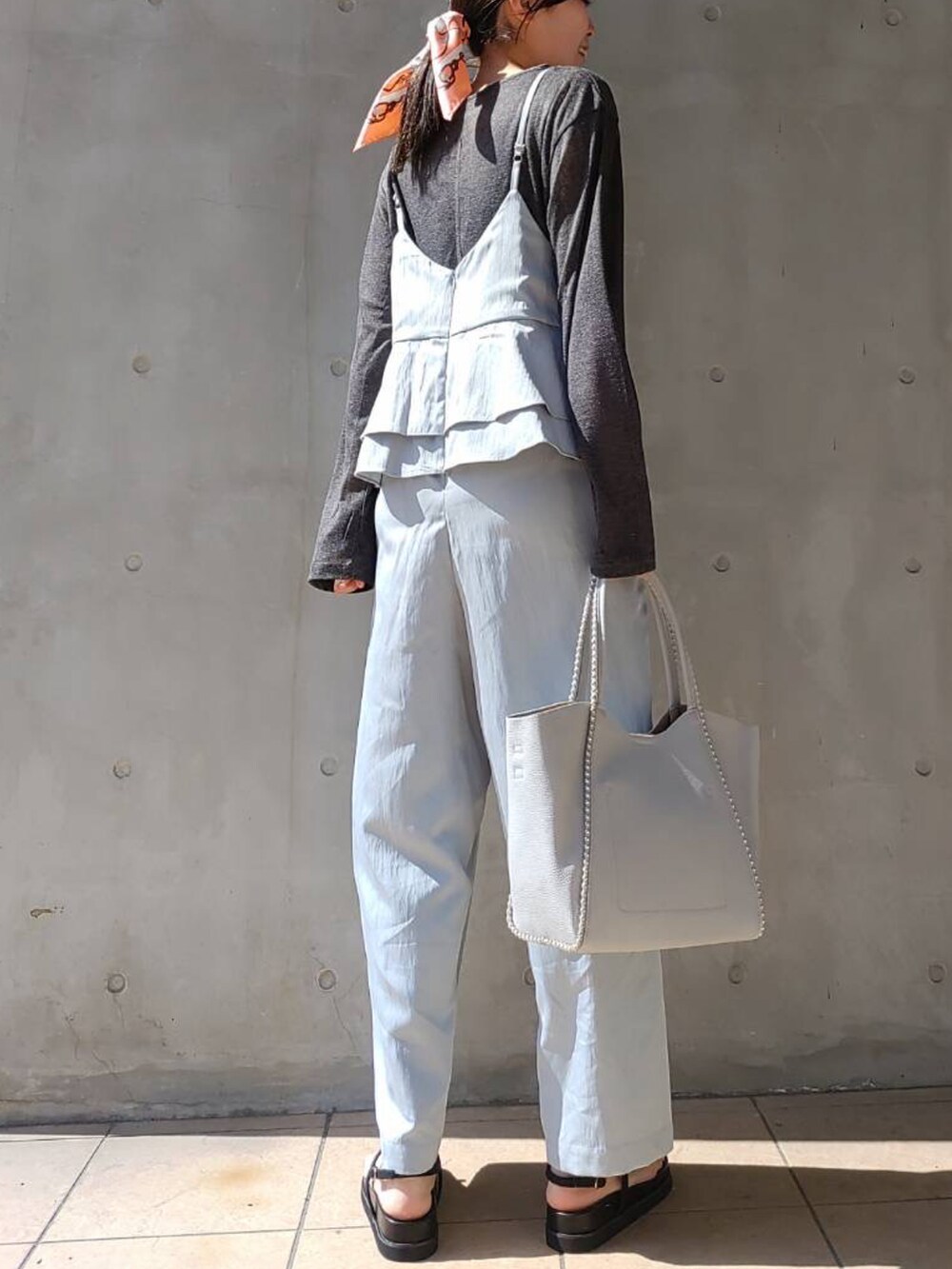 ブルー系のサロペット/オーバーオール、グレー系のTシャツ/カットソー、ブラック系のサンダルを着用したレディースの春コーディネートの2枚目の写真