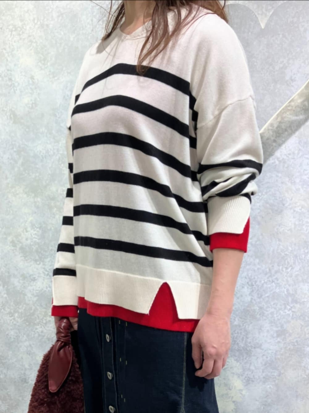 ブルー系のデニムスカート、レッド系のトートバッグ、ホワイト系のニット/セーターを着用したレディースの冬コーディネートの3枚目の写真