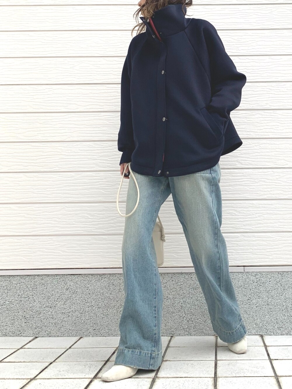 ブルー系のデニムパンツ、ホワイト系のショルダーバッグ、ブルー系のブルゾンを着用したレディースの冬コーディネートの2枚目の写真