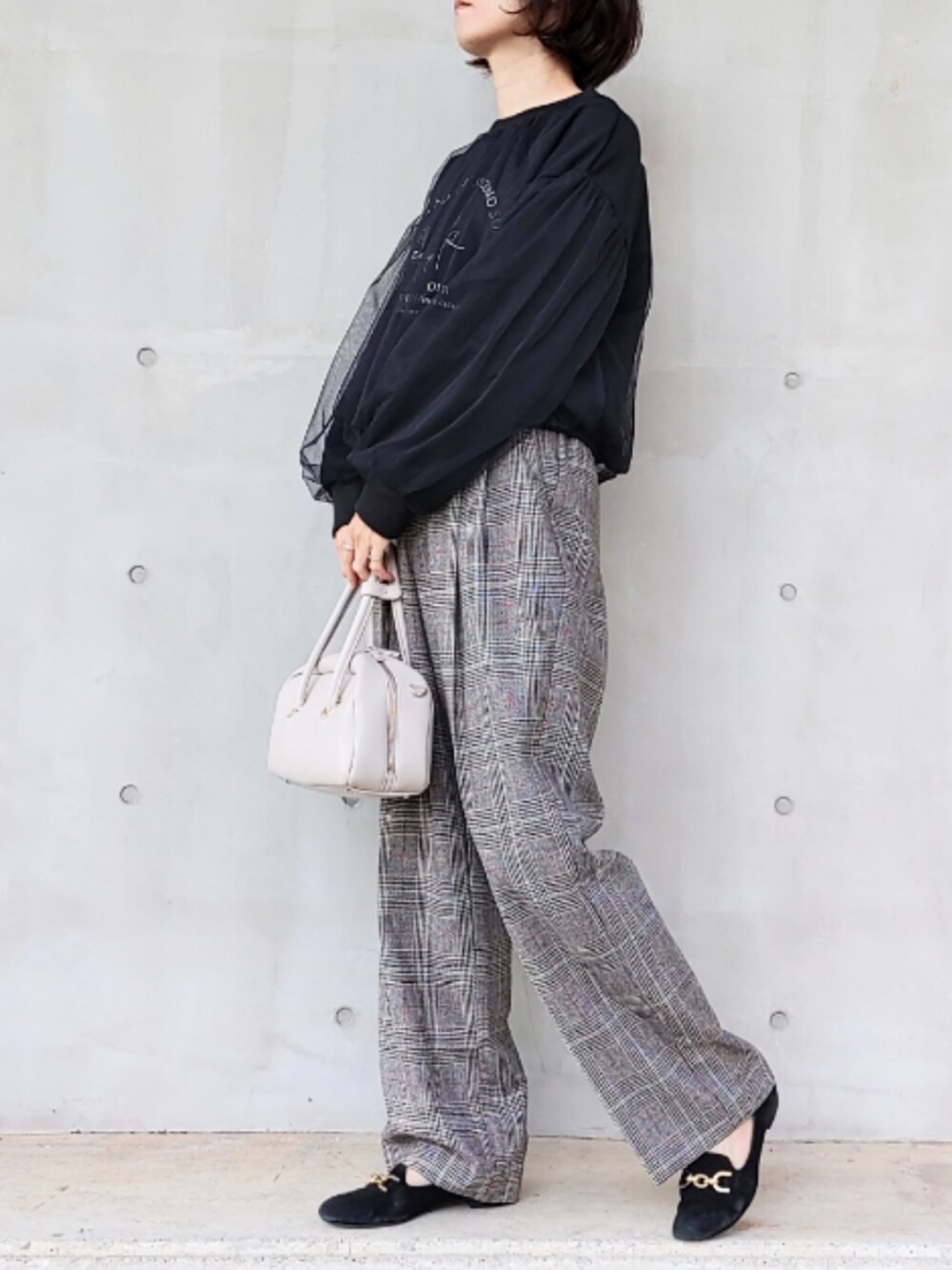 ブラック系のスラックス、ブラック系のスウェット、ホワイト系のボストンバッグを着用したレディースの秋コーディネートの3枚目の写真