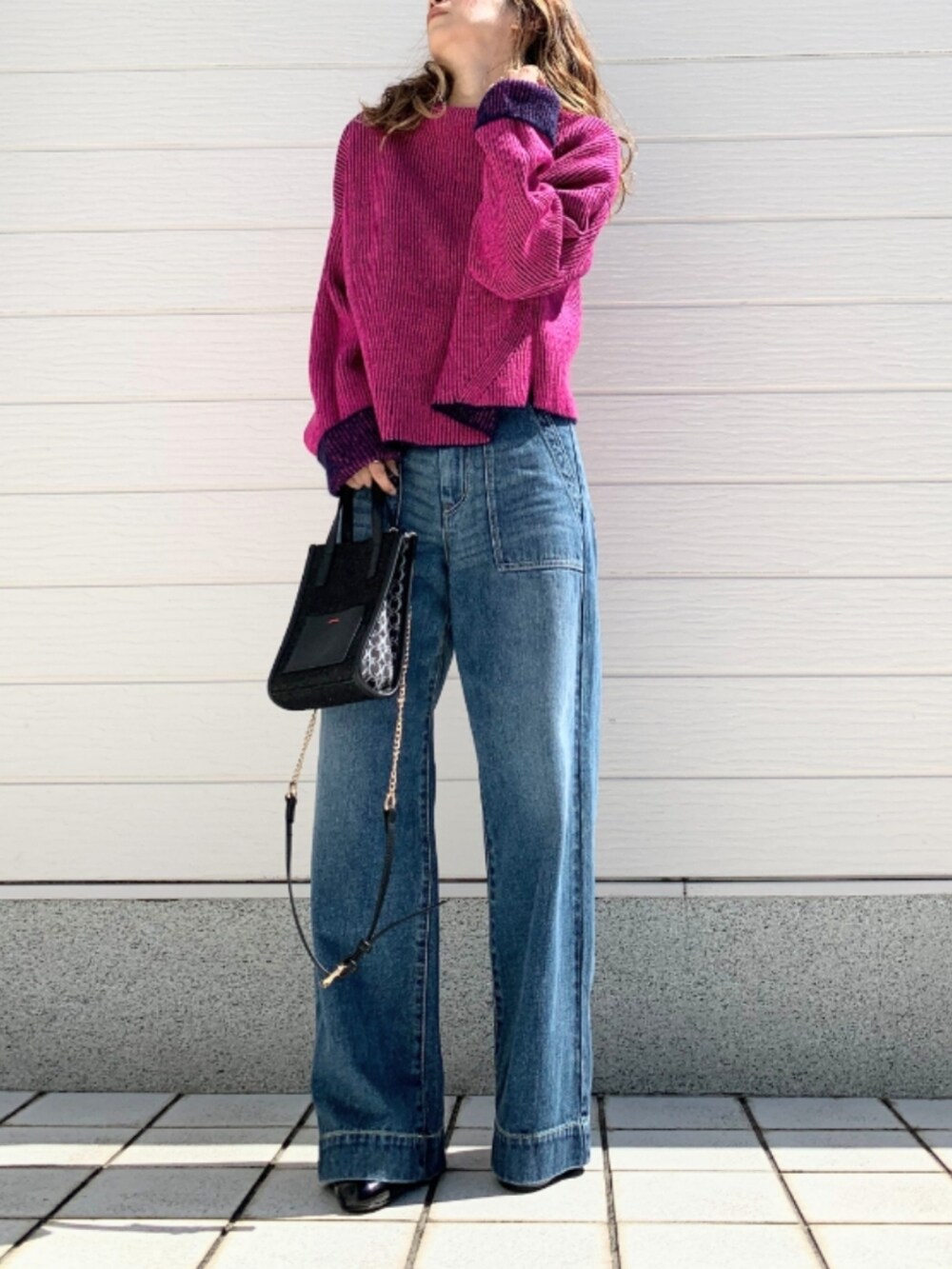 ブルー系のデニムパンツ、ブラック系のショルダーバッグ、ブルー系のニット/セーターを着用したレディースの秋コーディネートの2枚目の写真